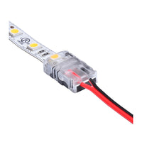 Close-up zijaanzicht van een LED strip connector met transparante behuizing en aangesloten rode en zwarte voedingsdraden op een LED strip.
