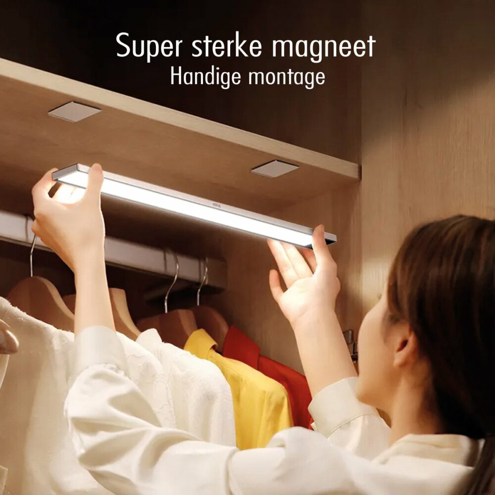 LED kastverlichting met super sterke magneetbevestiging, vooraanzicht van een persoon die de lamp onder een houten plank in een kledingkast monteert.