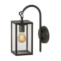 Zwart metalen wandlamp voor buiten in lantaarnstijl met glazen panelen en zichtbare LED filamentlamp, schuin vooraanzicht.