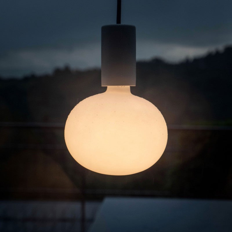 Hangende ronde designlamp met matglazen bolvormige kap, sfeervol verlicht in een avondsetting – vooraanzicht.