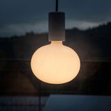 Hangende ronde designlamp met matglazen bolvormige kap, sfeervol verlicht in een avondsetting – vooraanzicht.